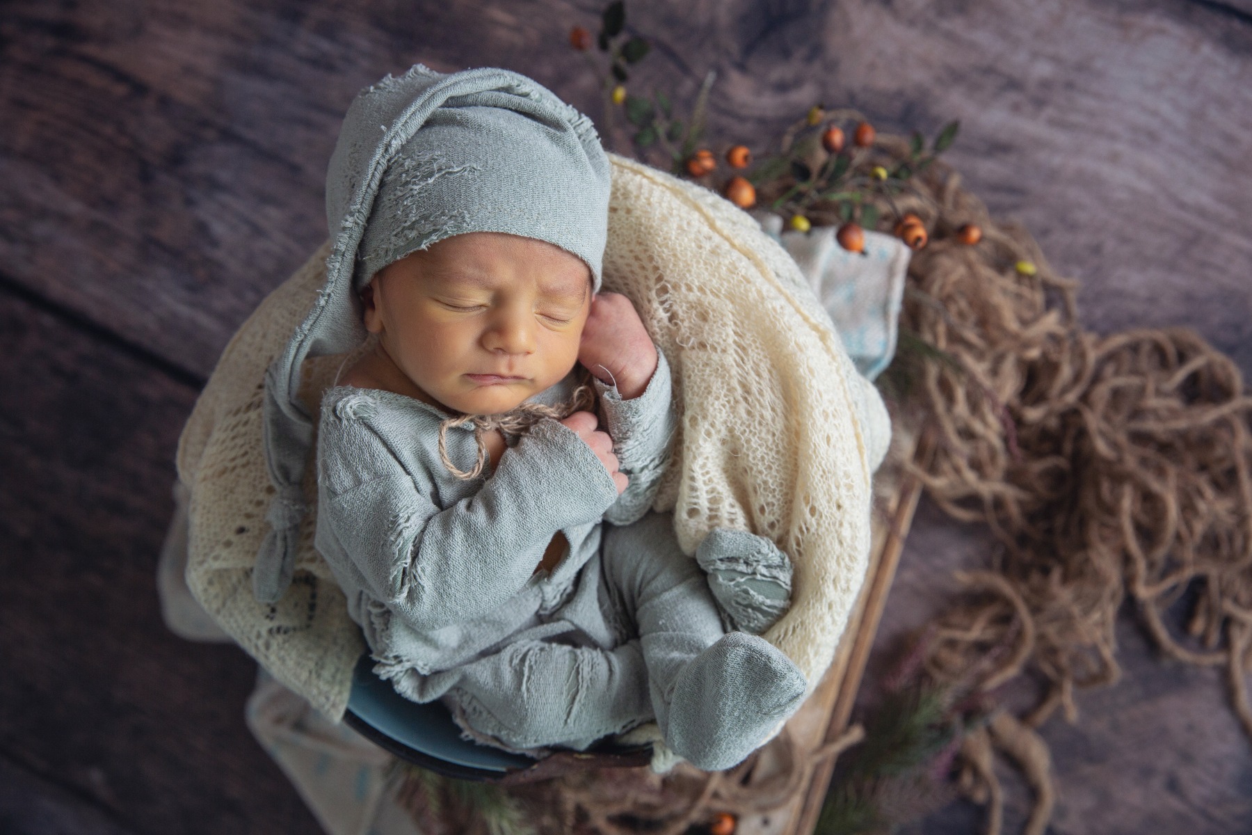 sleeping newborn in a green sleeper with stocking hat