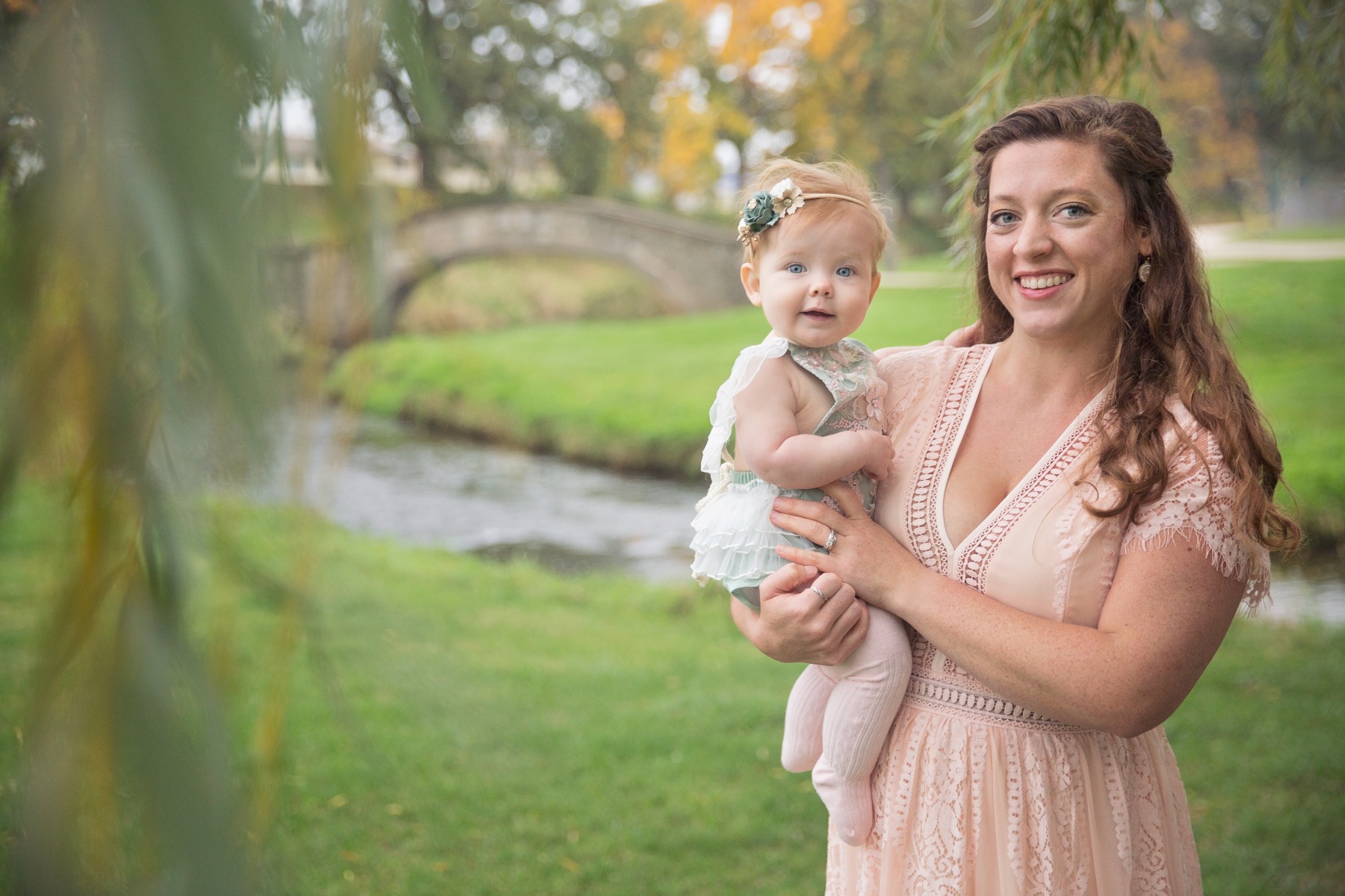 mom in pink dress poses with little girl beneath a willow tree