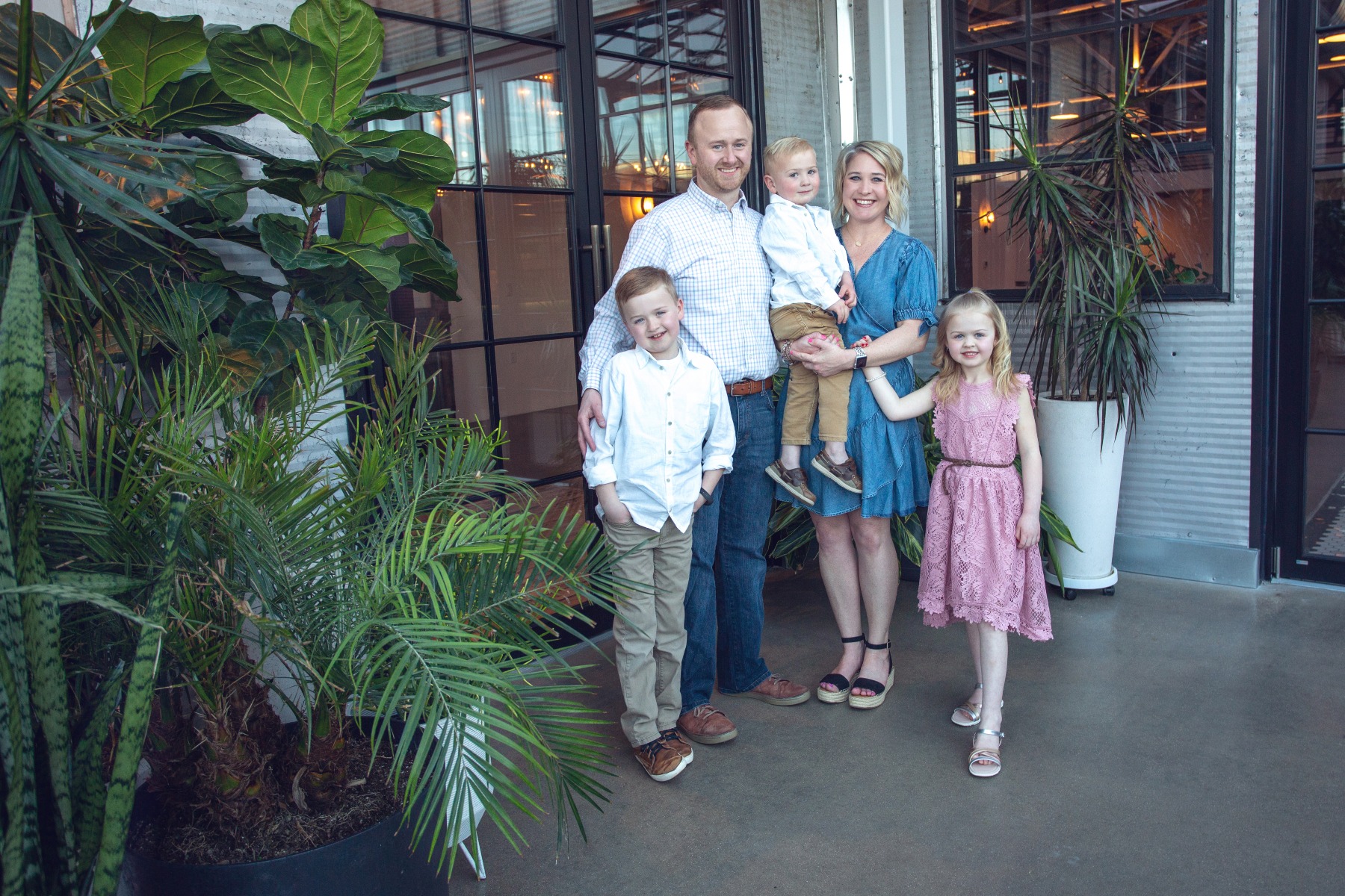 family of 5 pose in a metal/glass sunroom