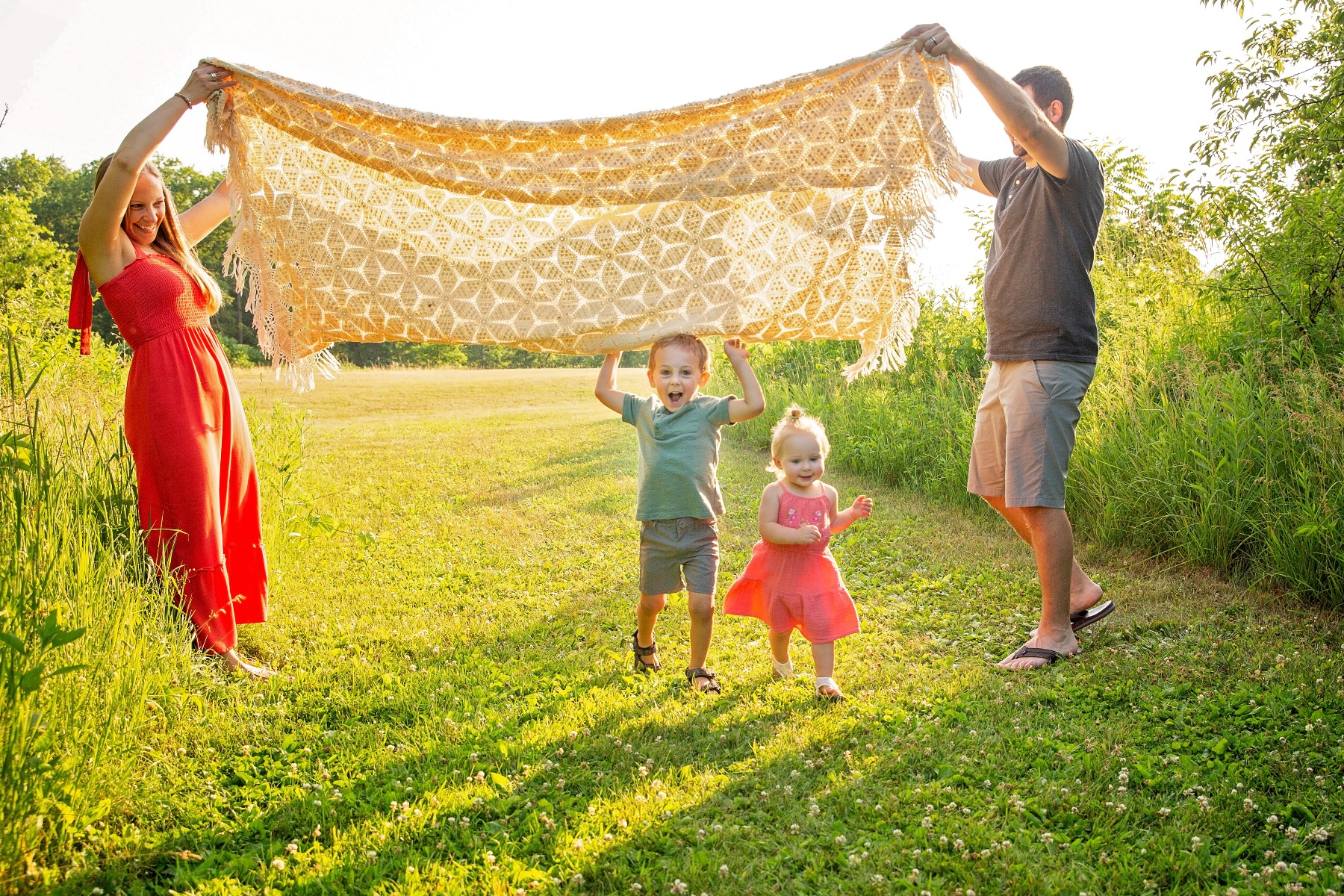 mom & dad hold blanket up as two young children play under it