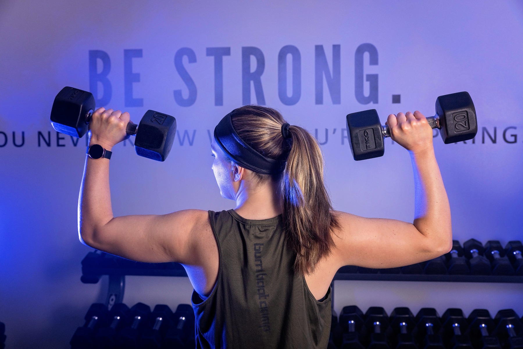 weight lifter holds barbells to either side of her shoulders