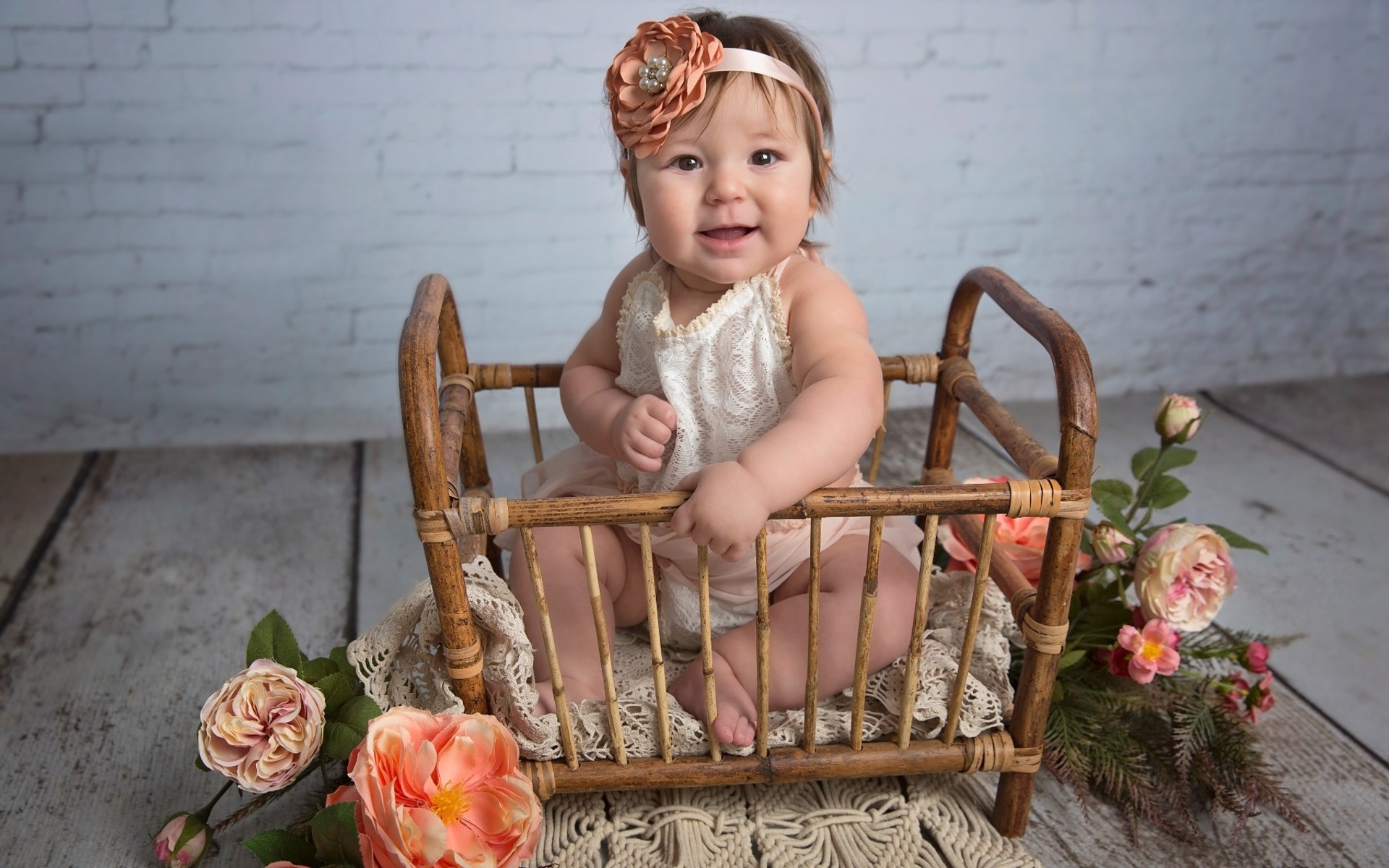8 month old baby girl sits in a bamboo crib surrounded by flowers