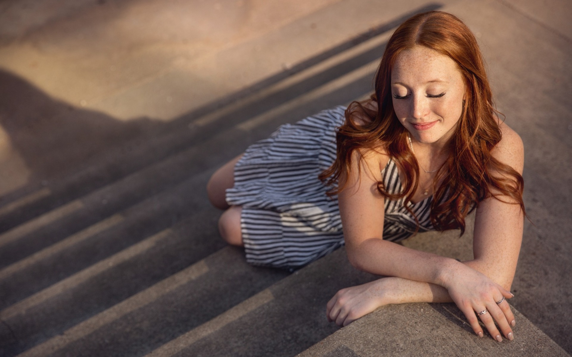 red haired hs senior girl sits on a stone stairwell