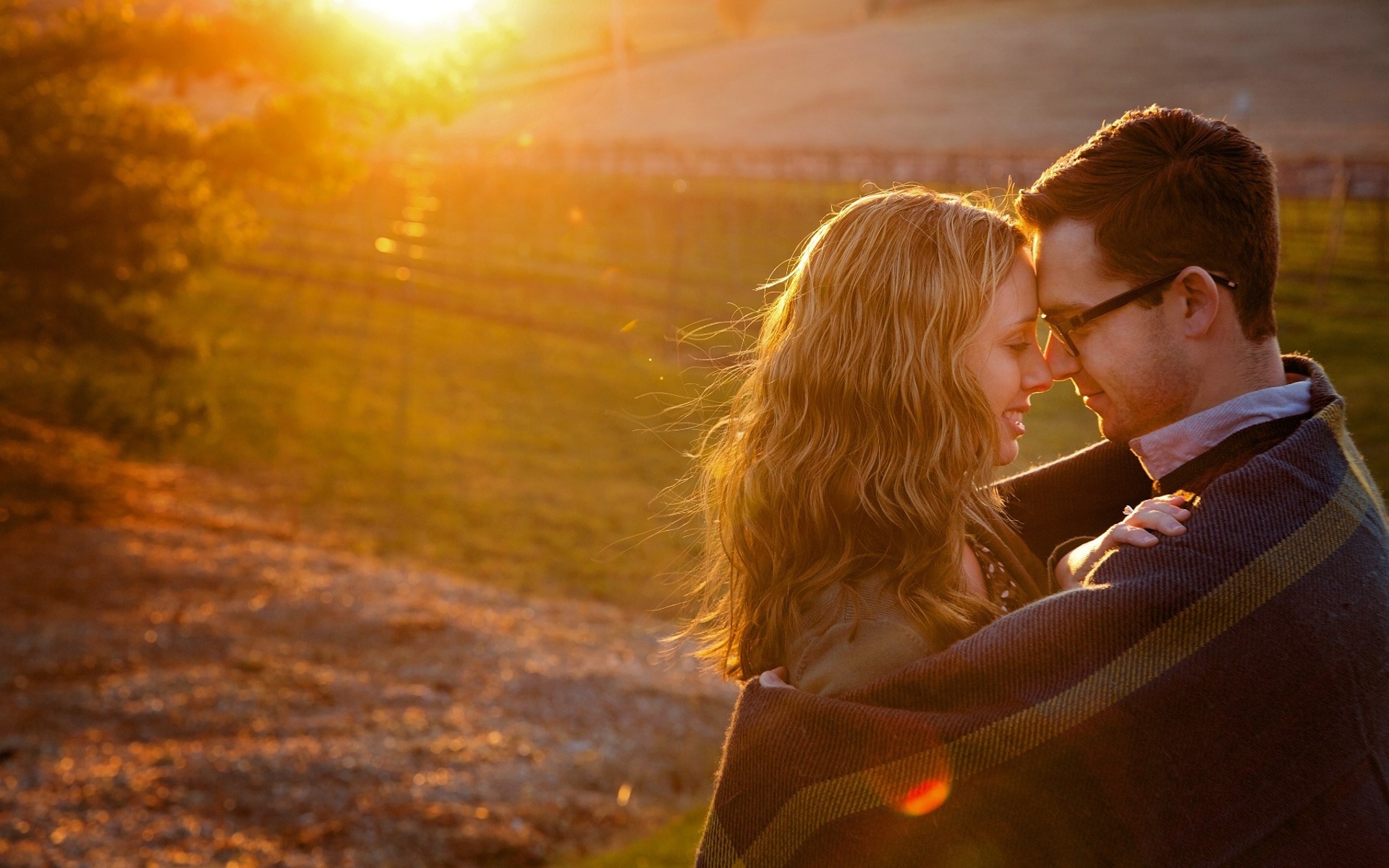 couple embrace under a blanket warmth by the setting sun