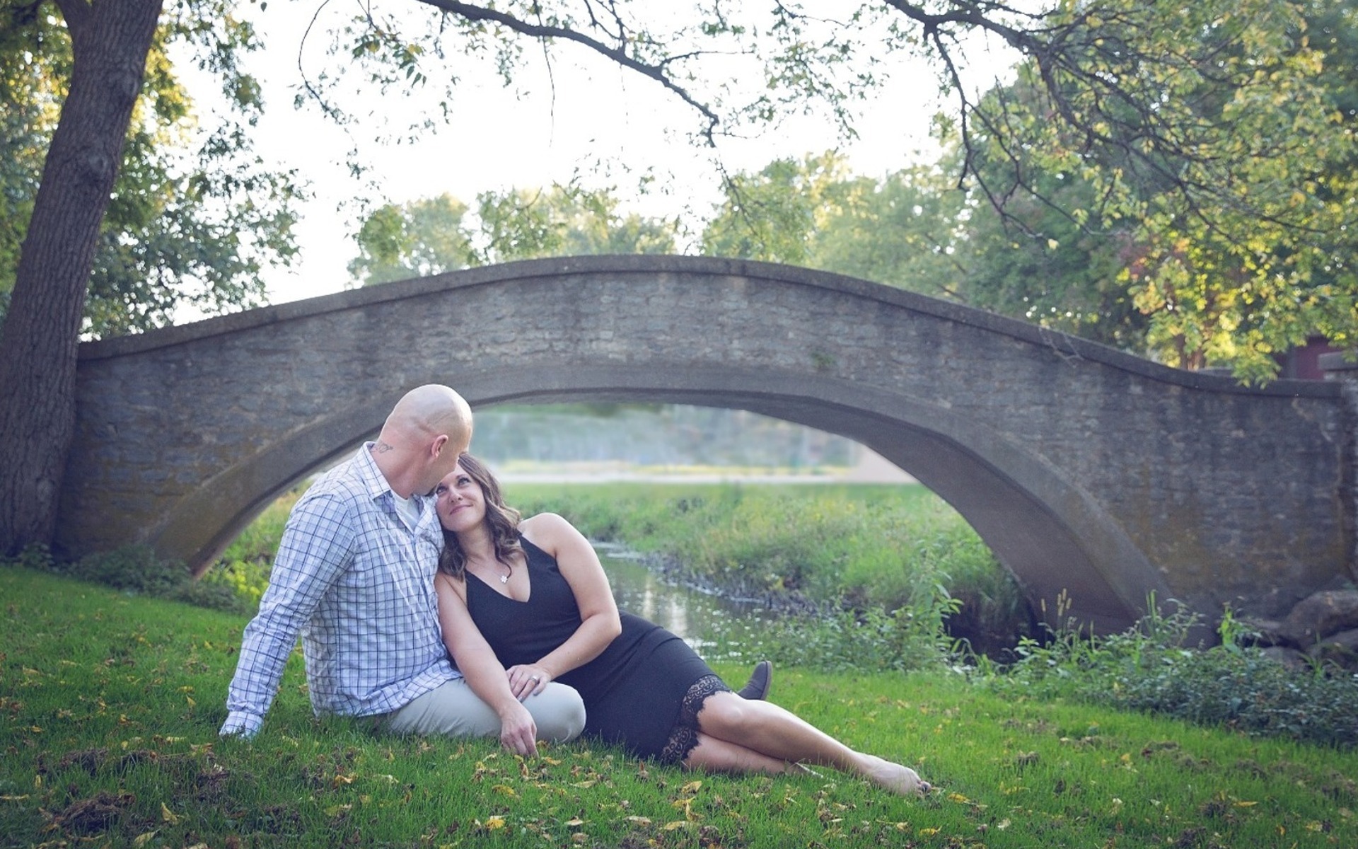 man & woman lay together in front of a stone bridge