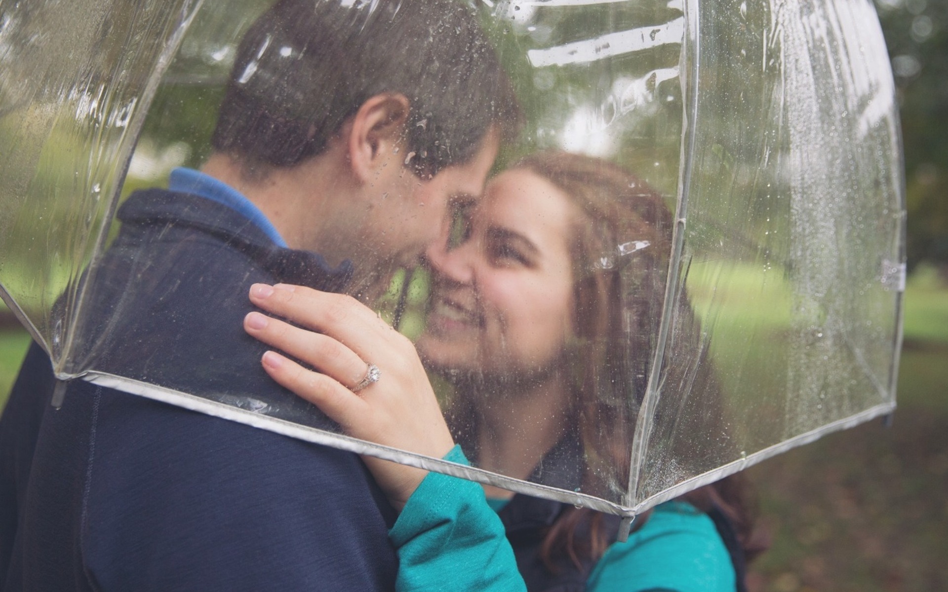 engaged couple embrace under a rainy umbrella