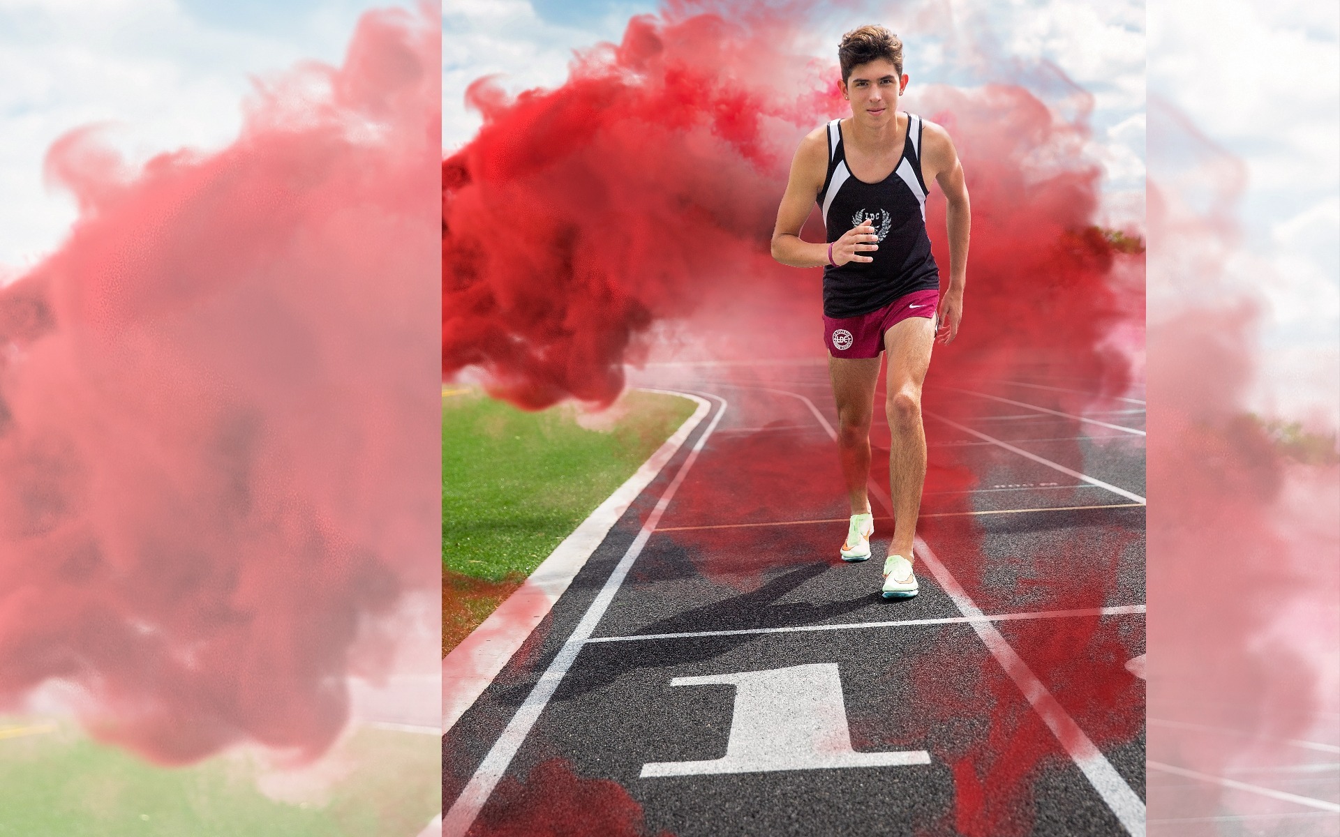 hs senior boy stands on a track starting block with red smoke all around