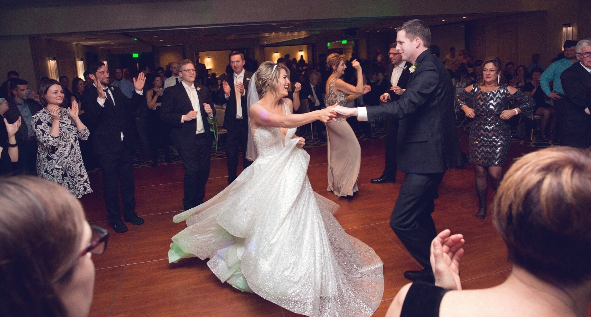 groom spins his bride on a packed dance floor