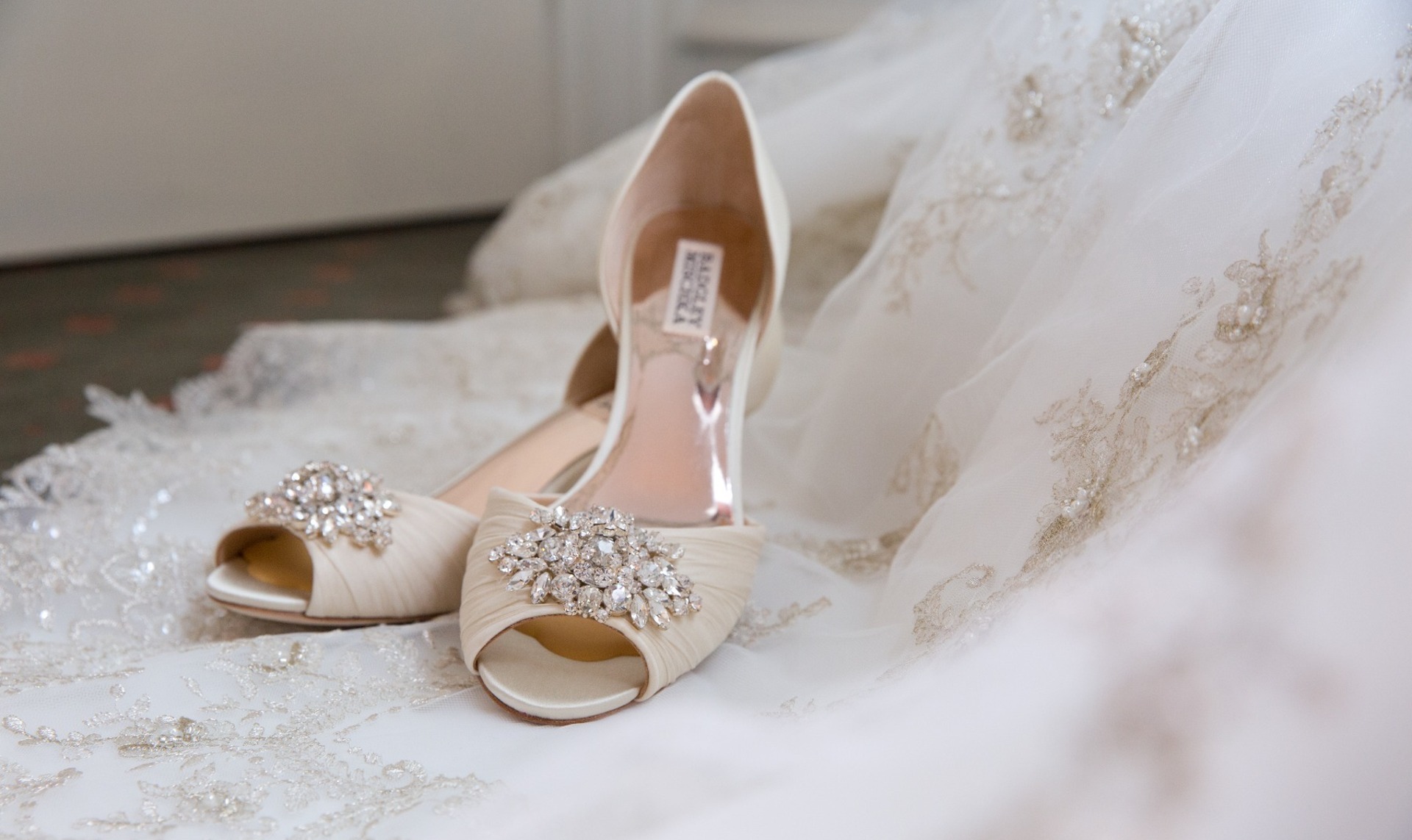 pair of white heels with silver rinestones sit on a white dress