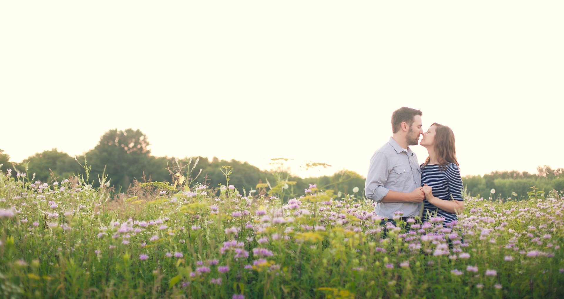 couple stand nose to nose in a field of purple flowers