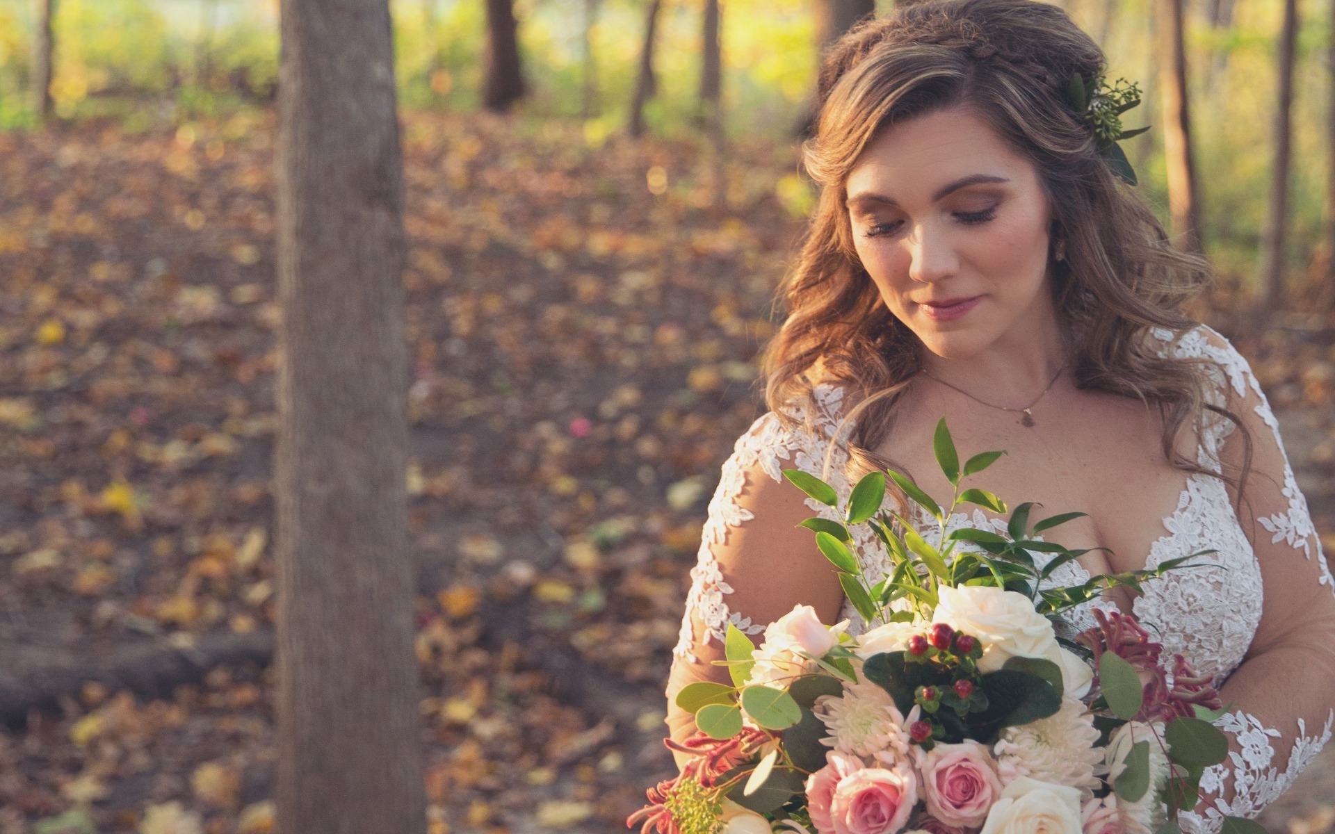 bride looks down at her bouquet in a fall setting