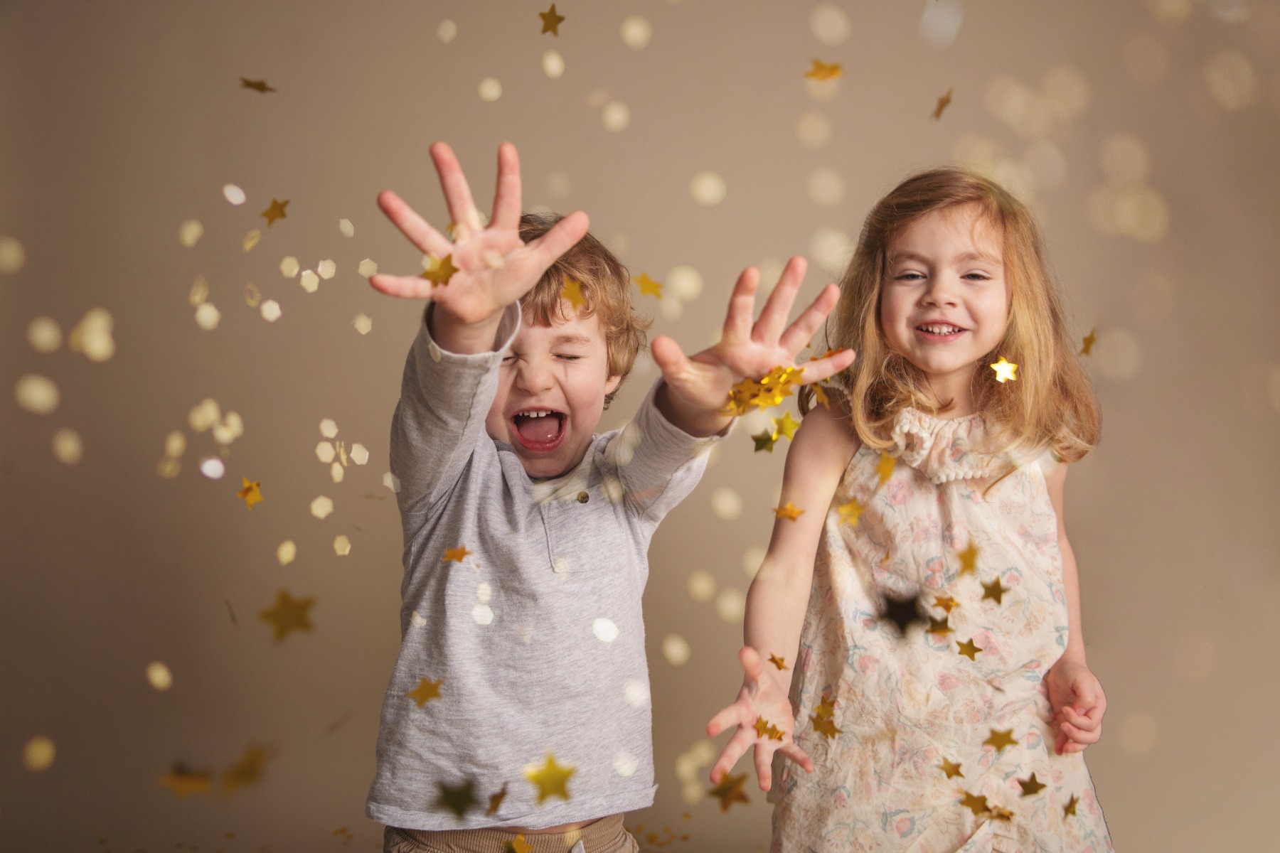brother and sister throw gold glitter at the camera