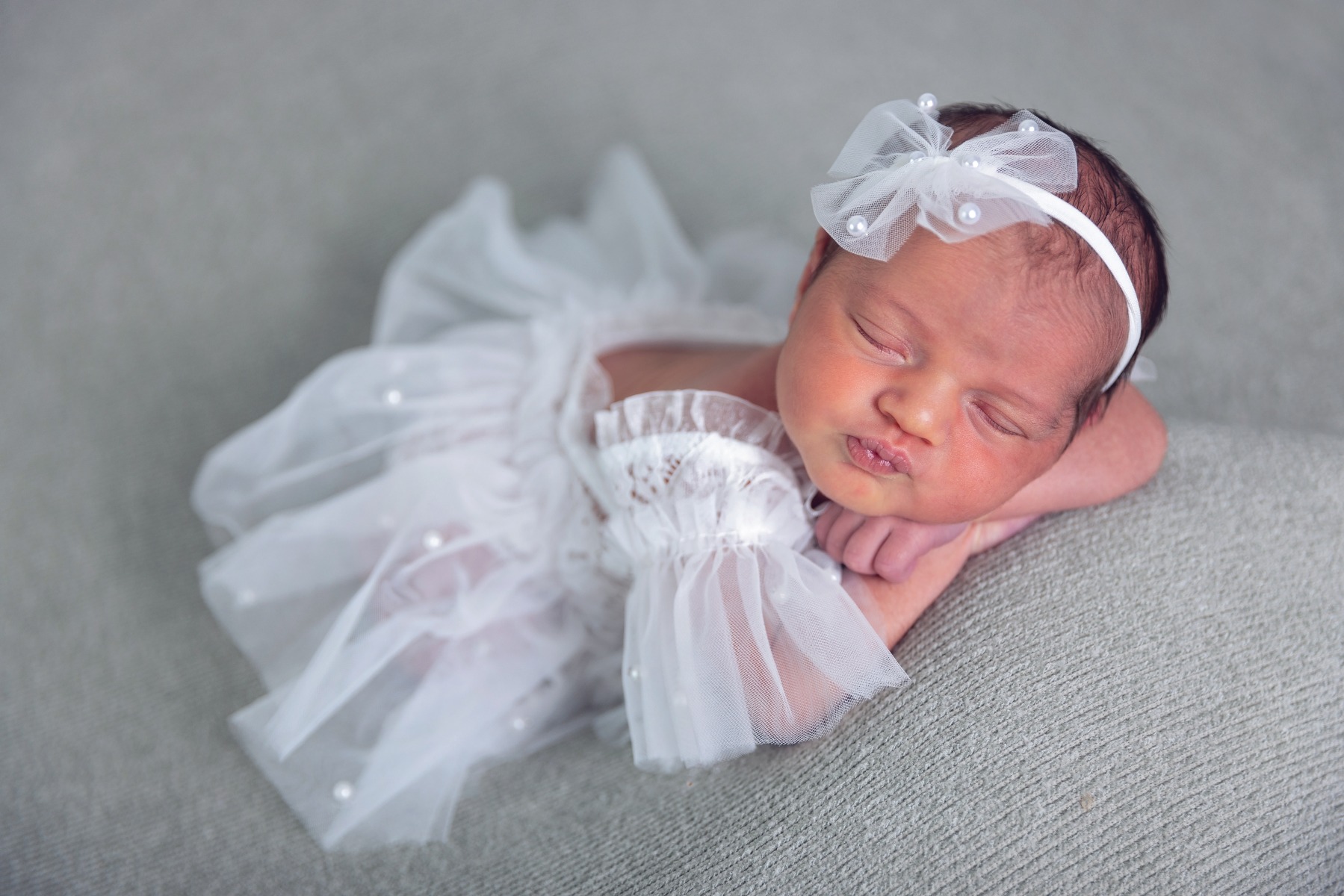 newborn baby sleeping on belly in white tulle outfit