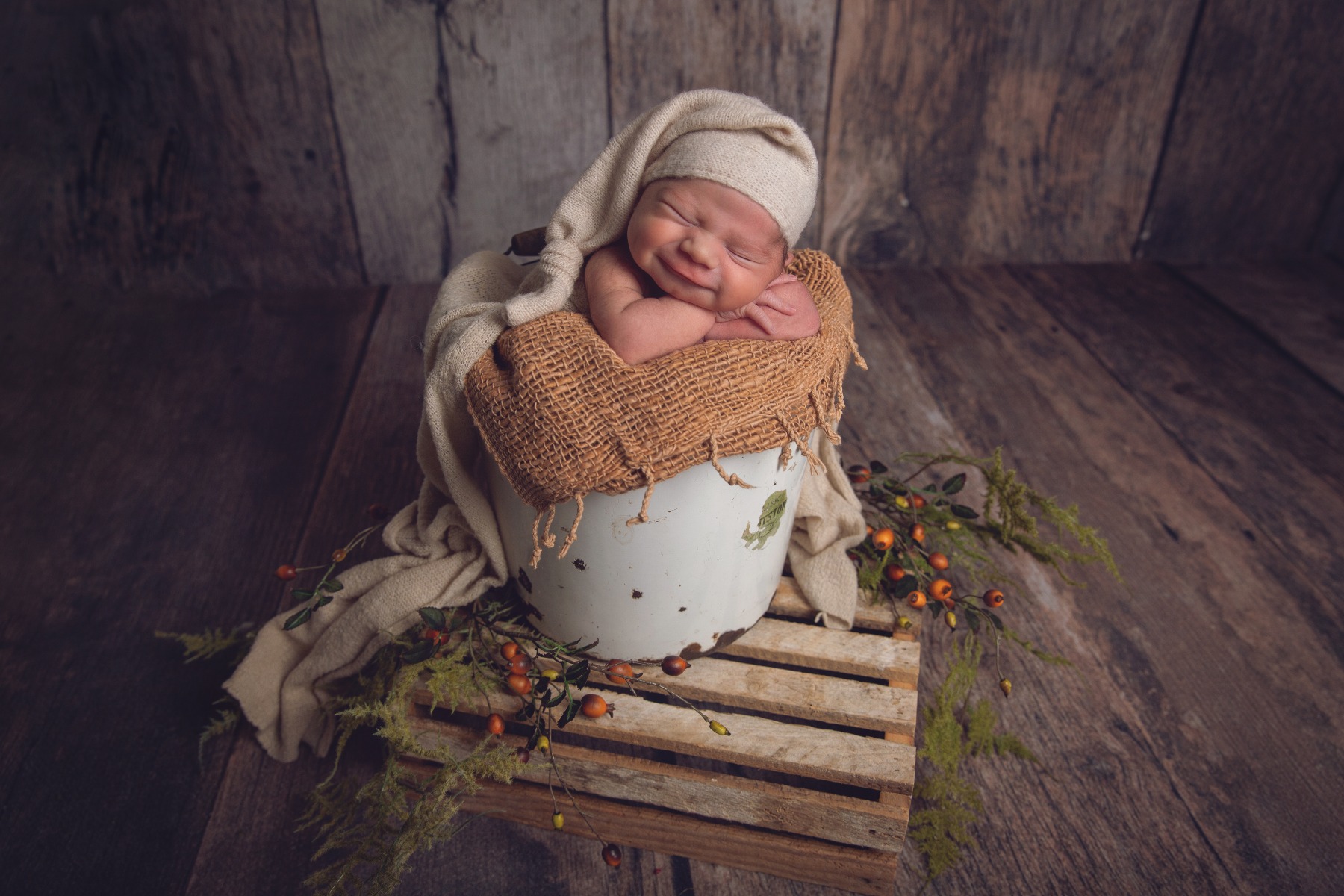 newborn baby in bucket smiling in his sleep