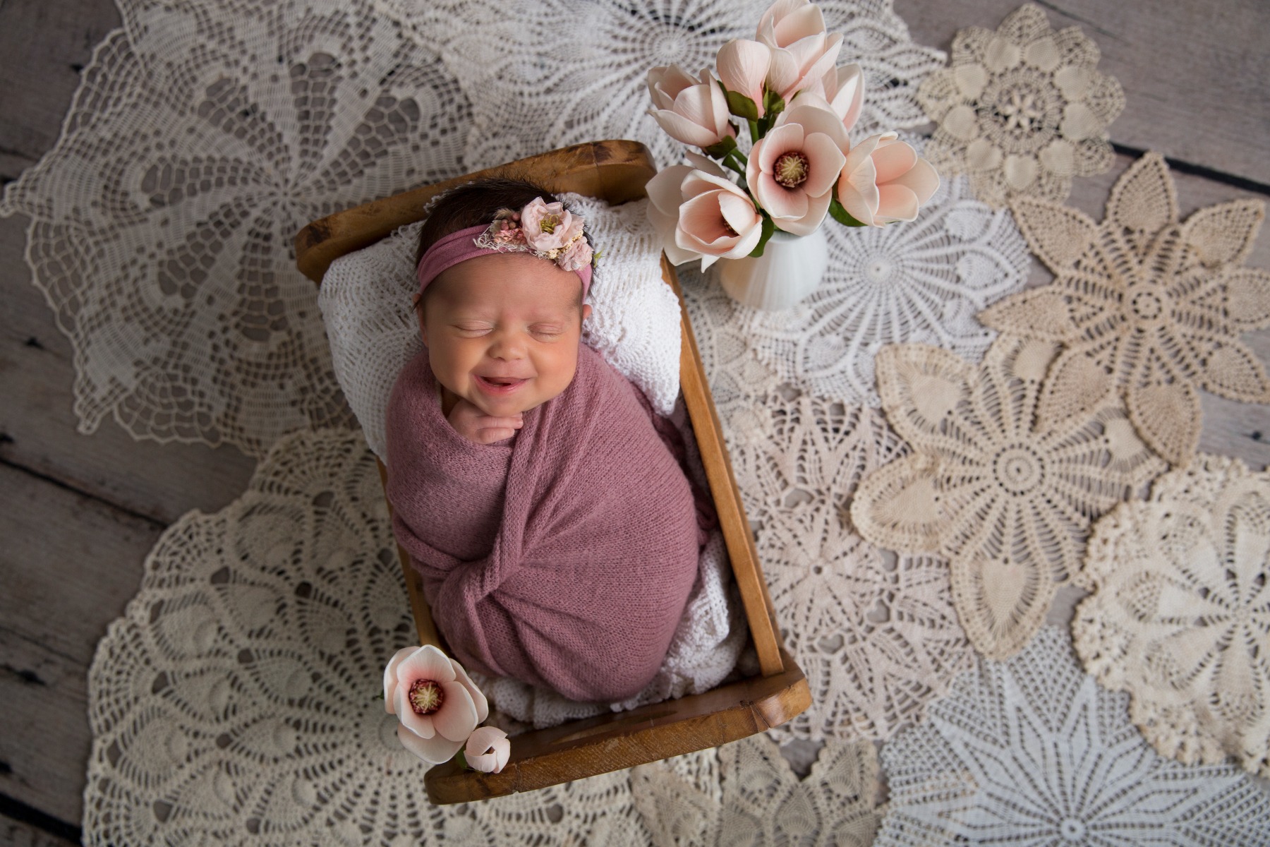 newborn girl smiling in her sleep amidst vintage doileys