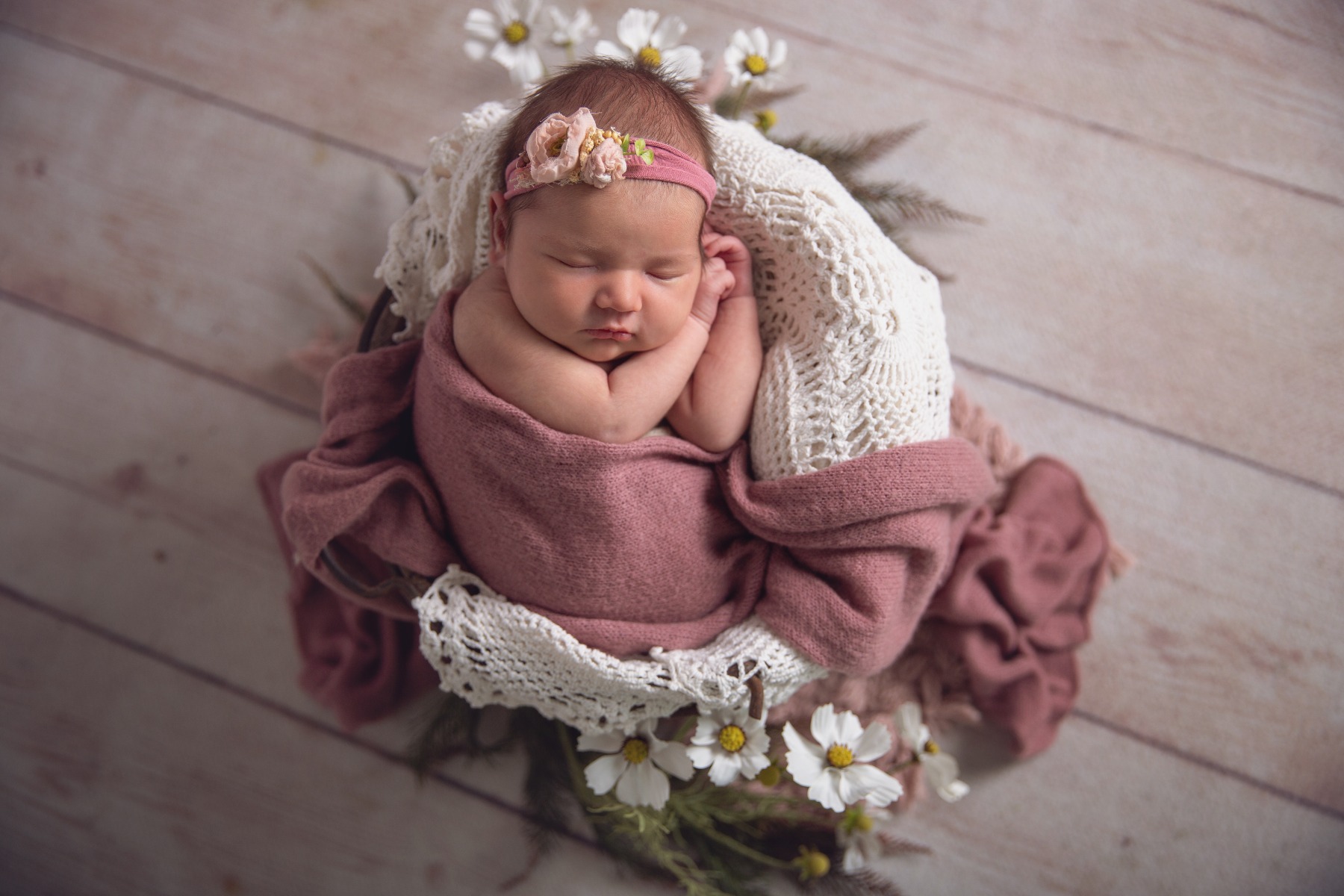 sleeping newborn wrapped in pink with white flowers