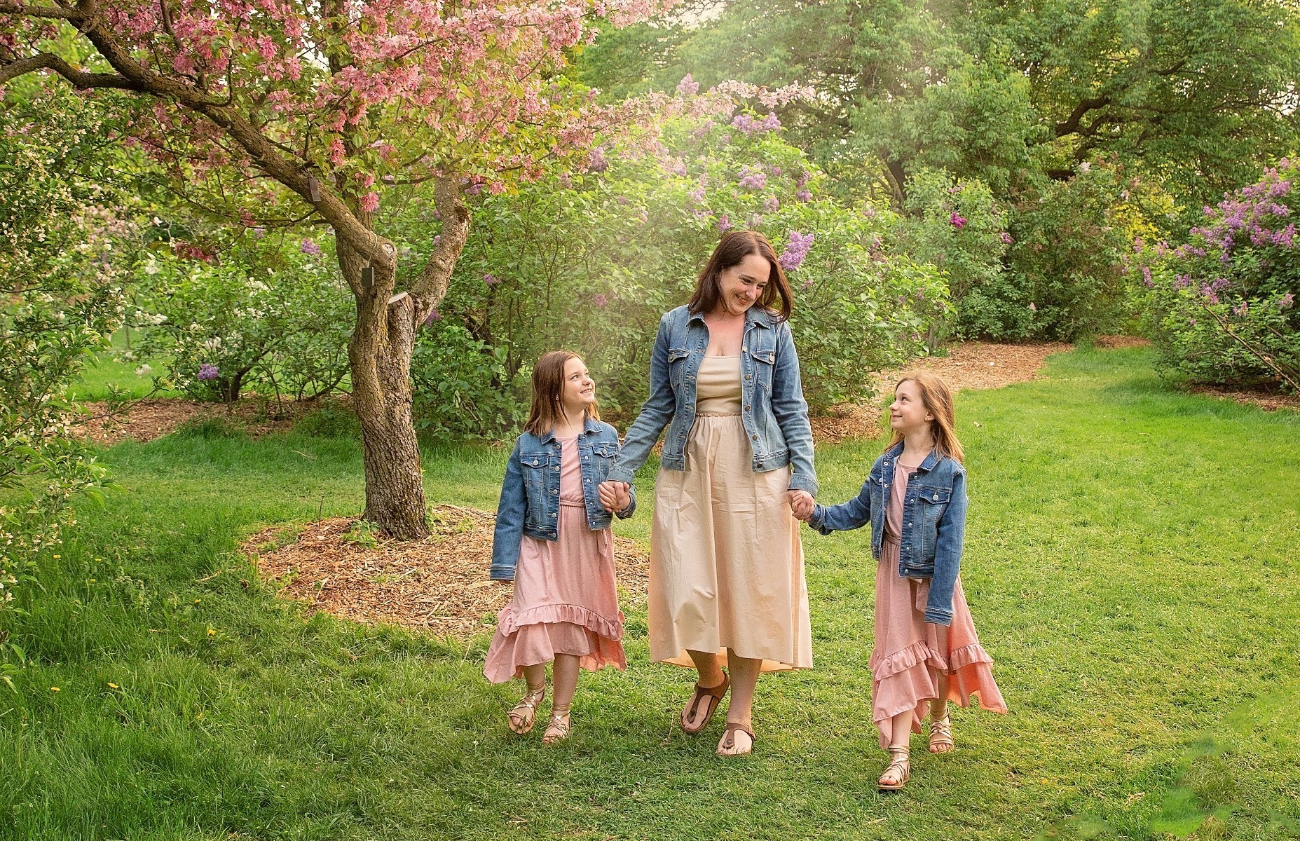 mom walks with her twin daughters at a spring garden
