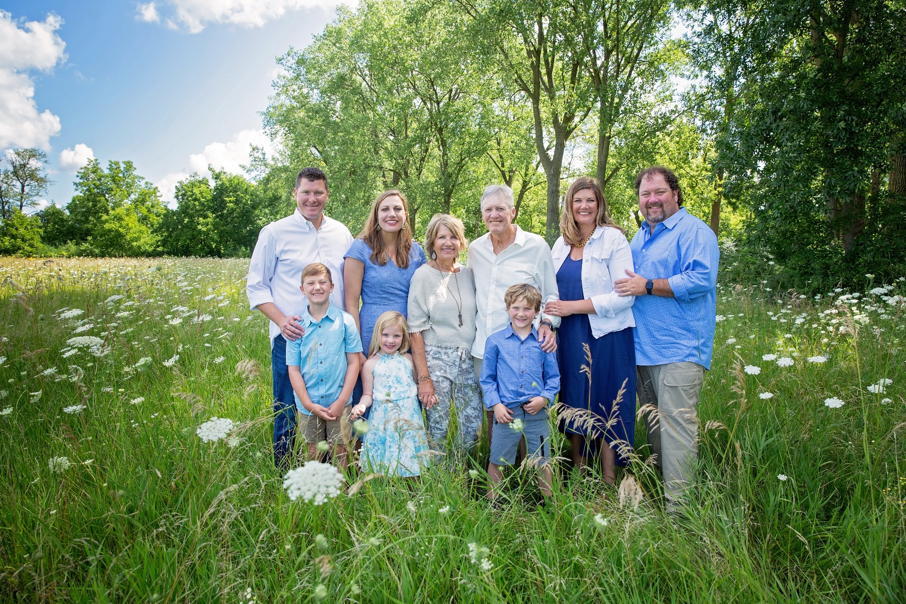 group of 9 families members in shades of blue in a grassy field