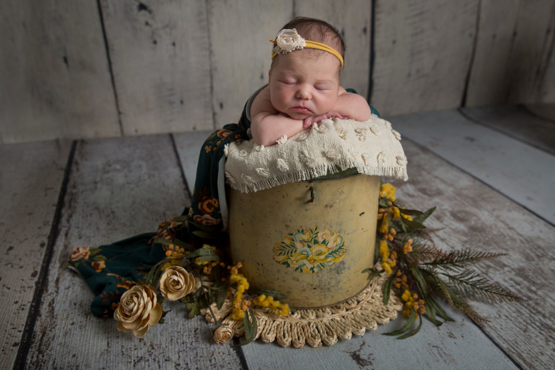 newborn girl sleeping in a yellow bucket