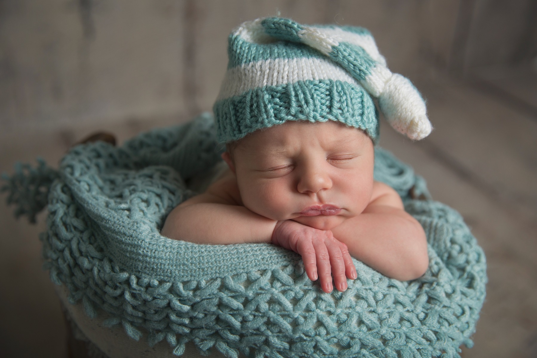 newborn baby in a teal & white sleep cap