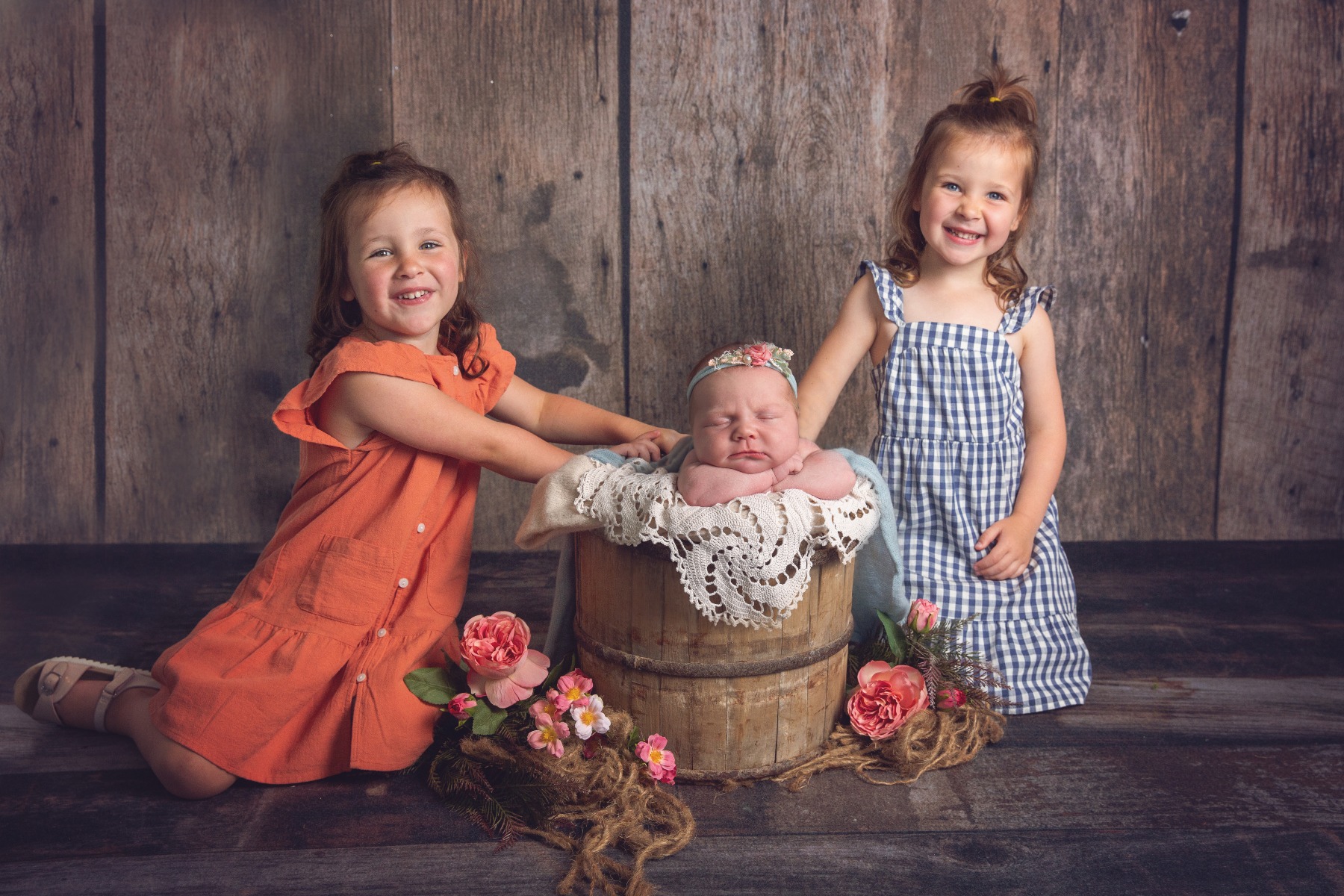 two sisters pose with their new baby sister