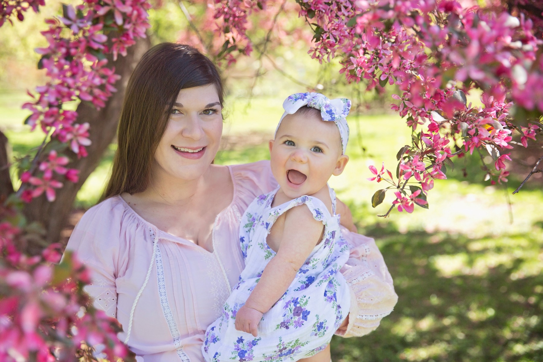 mom and baby girl beneath a pink cherry tree