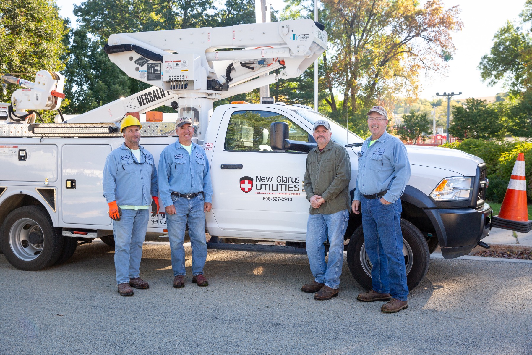 4 employees of the New Glarus utilities company pose by a truck