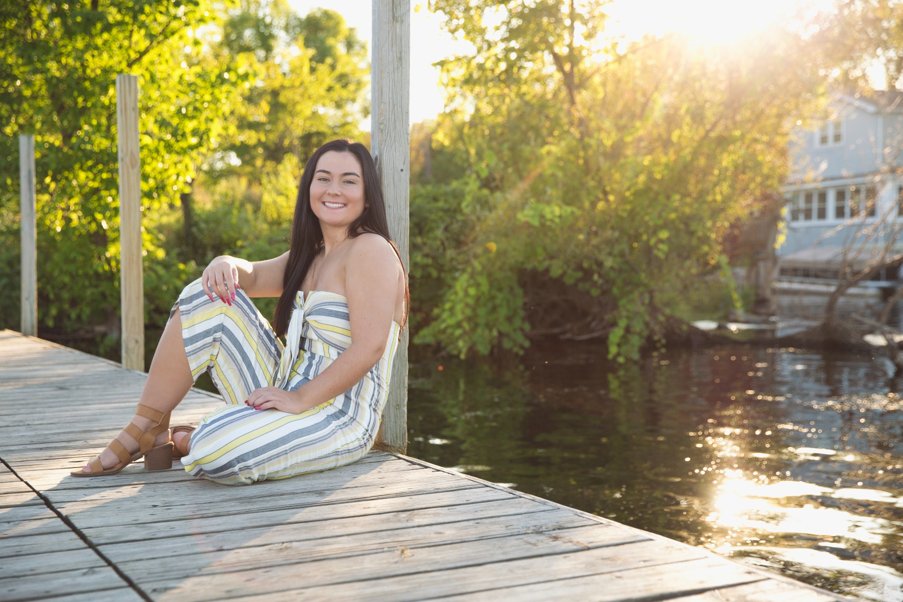 senior girl sits on a dock by the lake