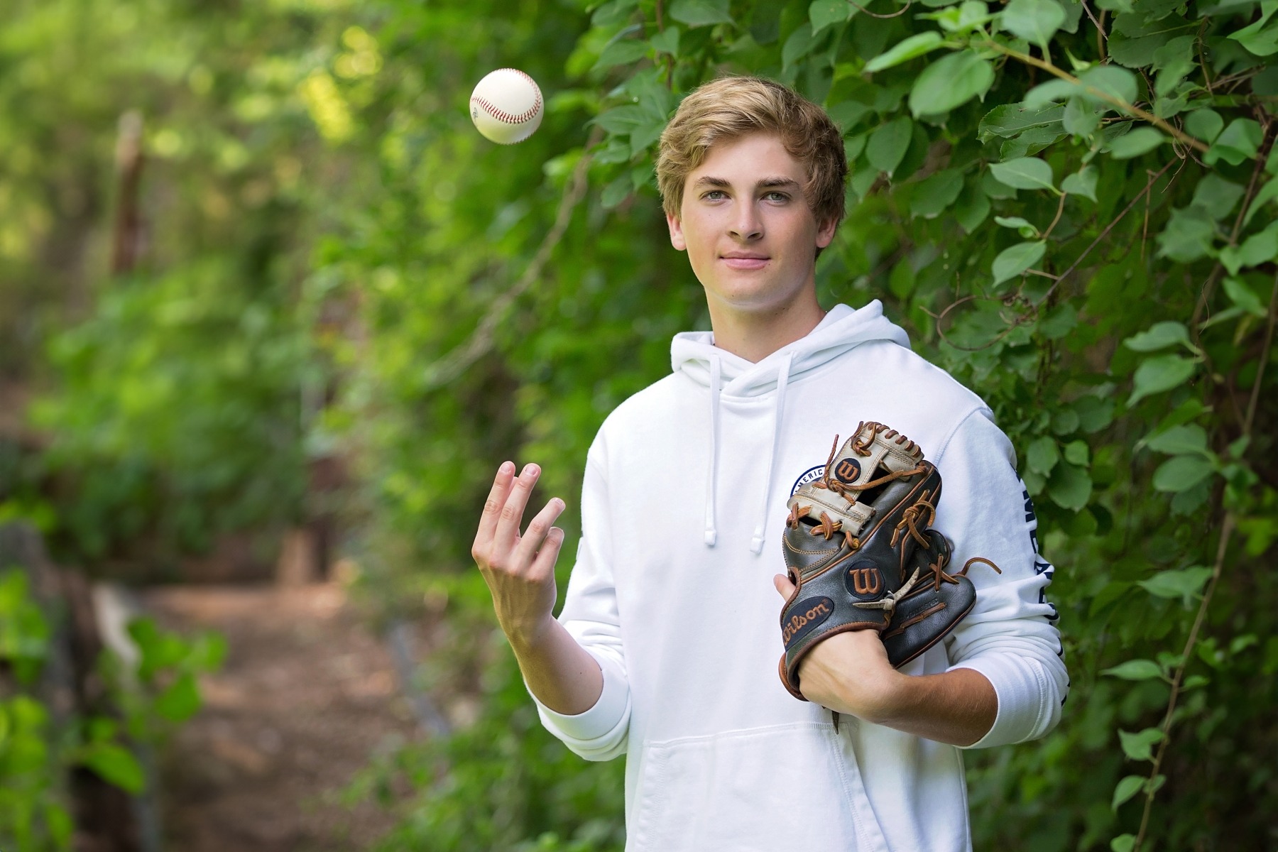 hs senior boy is tossing a baseball in the air