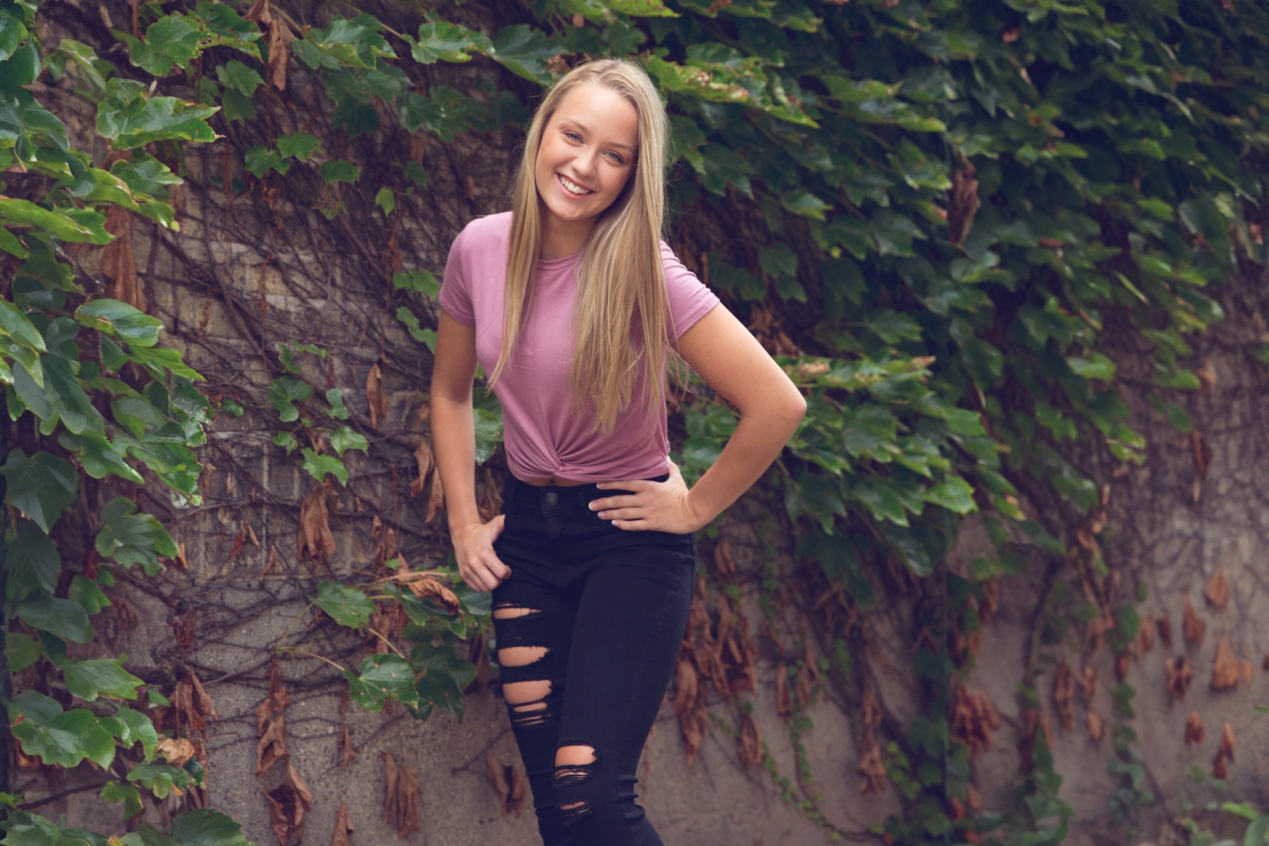 blond senior girl in front of an ivy wall