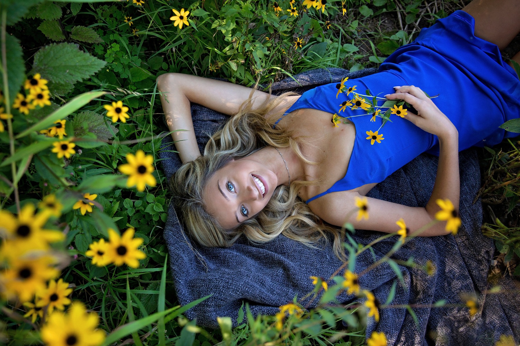 hs senior girl lays on a blanket amongst the yellow flowers