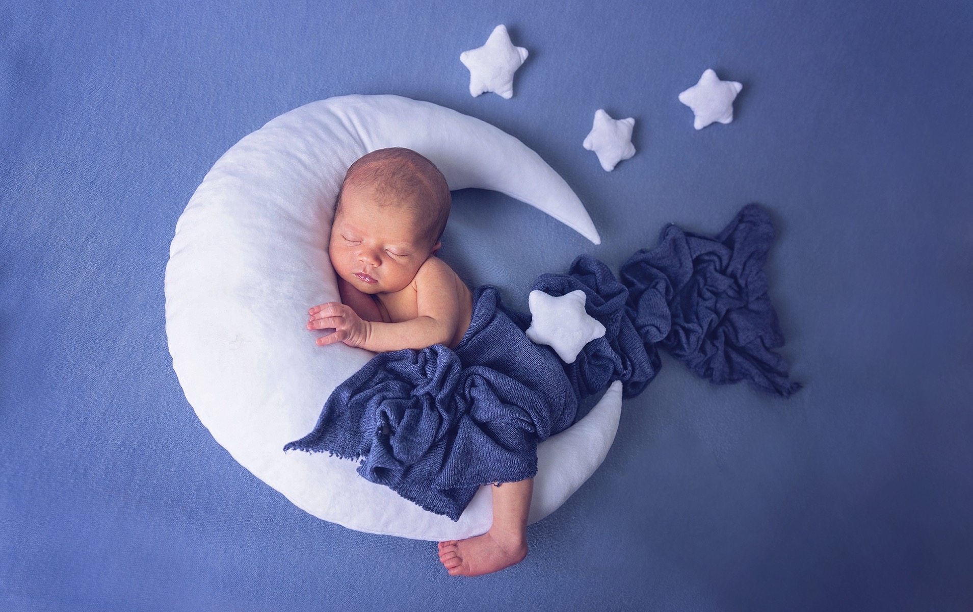 newborn baby boy sleeps on a pillow shaped moon