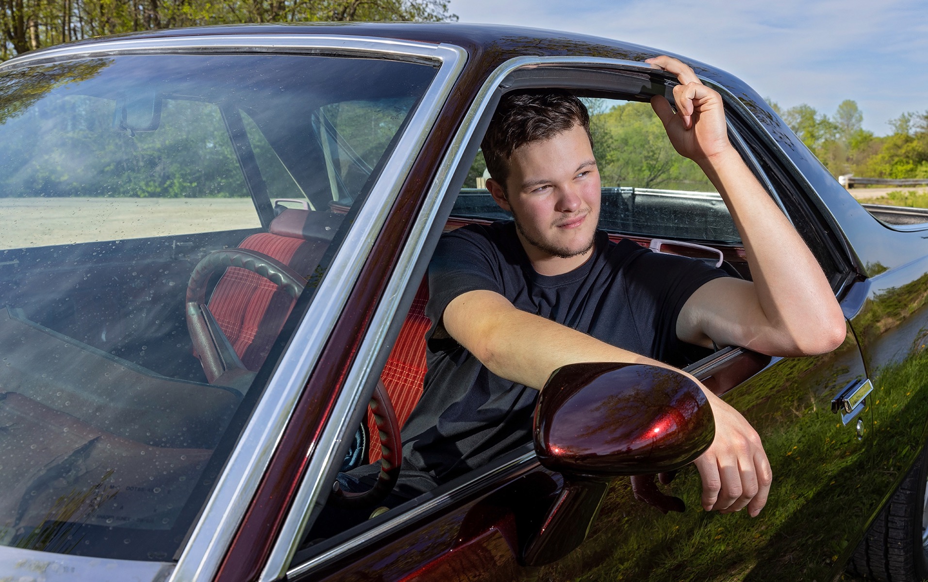 high school senior boy poses out the window of his vehicle
